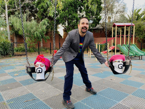 Jeremy Moses gleefully pushes costume-clad foam heads on playground swings.